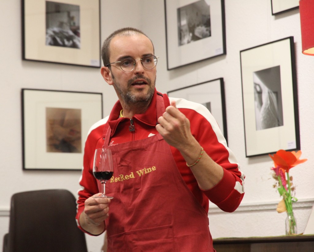Jeremy Debreu en tablier Red Red Wine présentant un vin, un verre de rouge à la main