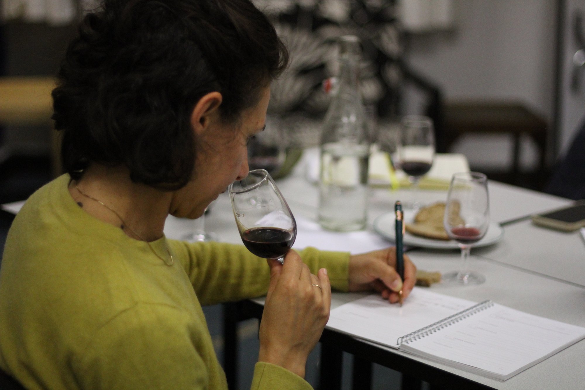 Une abonnée sent son verre de vin rouge en prenant des notes
